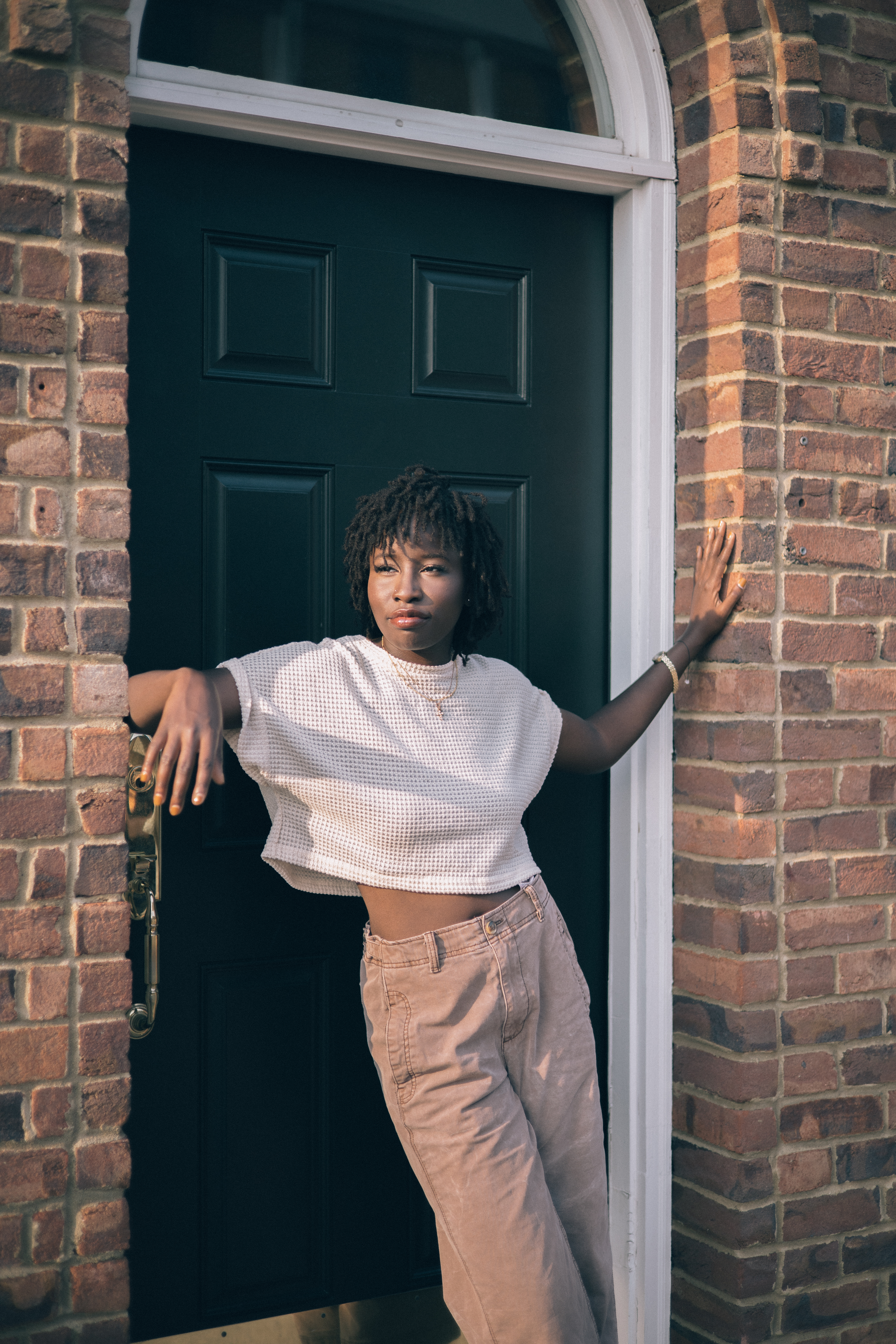 Woman leans against a brick wall and doorway in a casual portrait