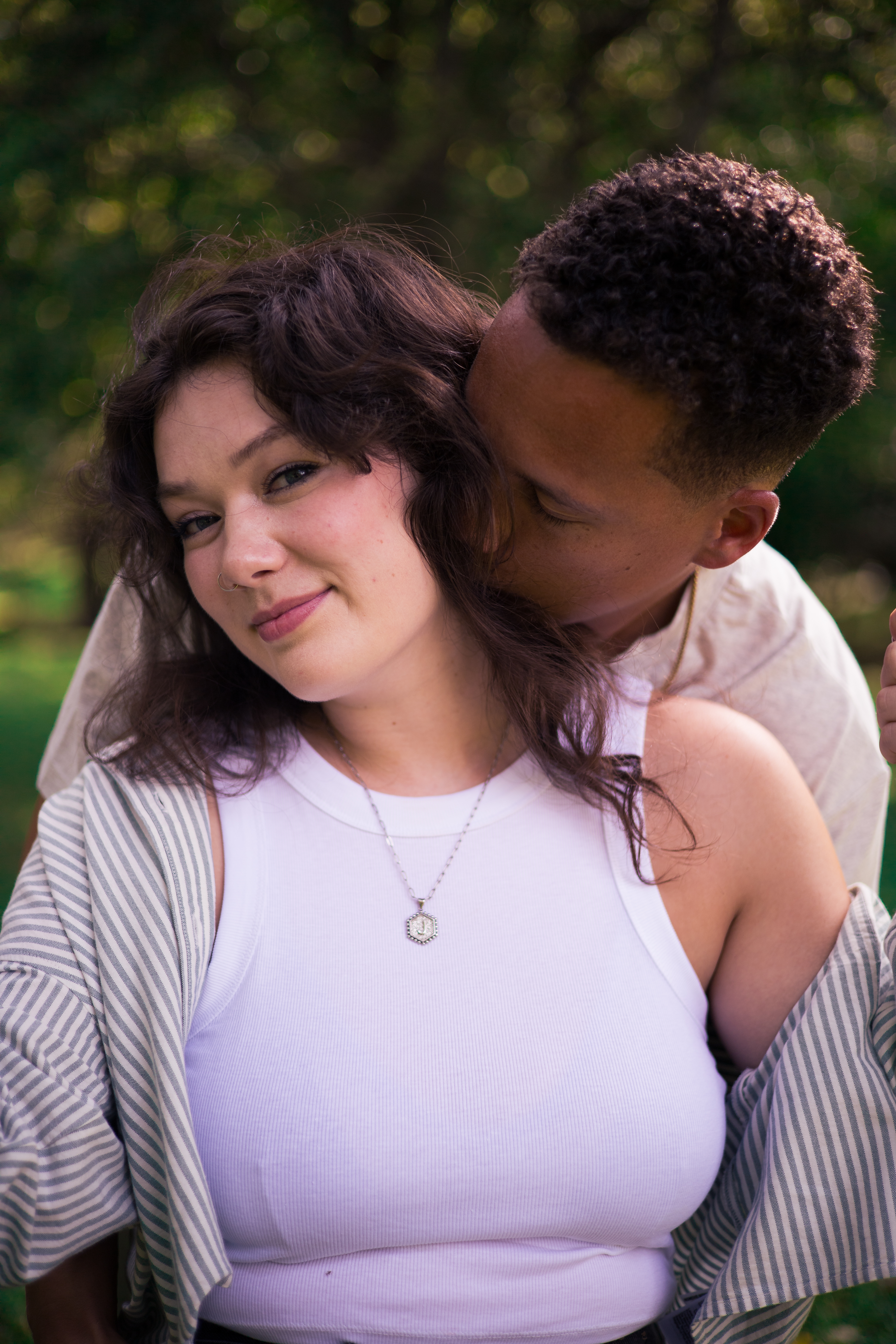 A man whispers to a woman as they embrace outdoors with a soft, romantic mood