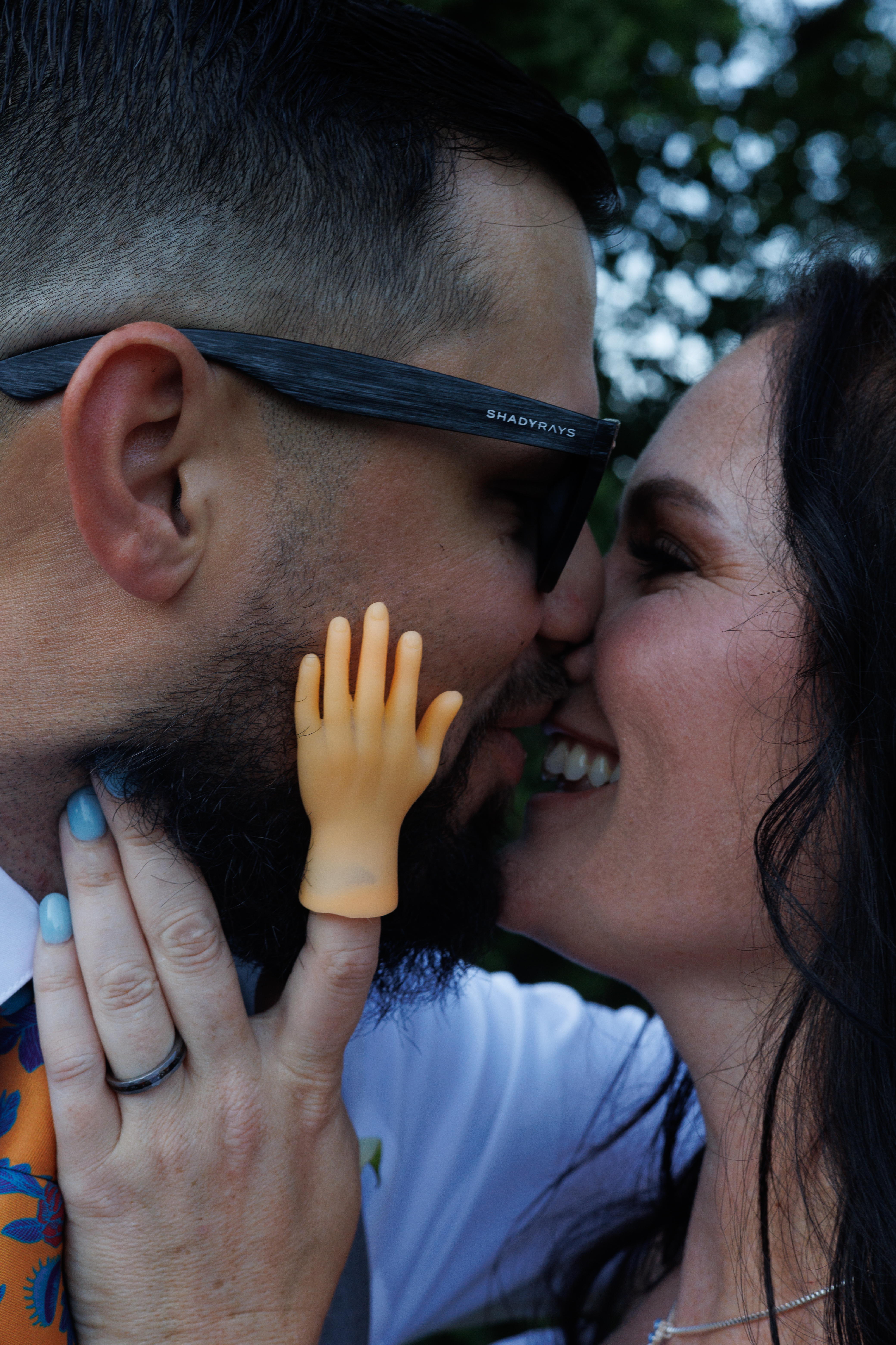 Playful wedding portrait of a couple kissing with a finger puppet hand