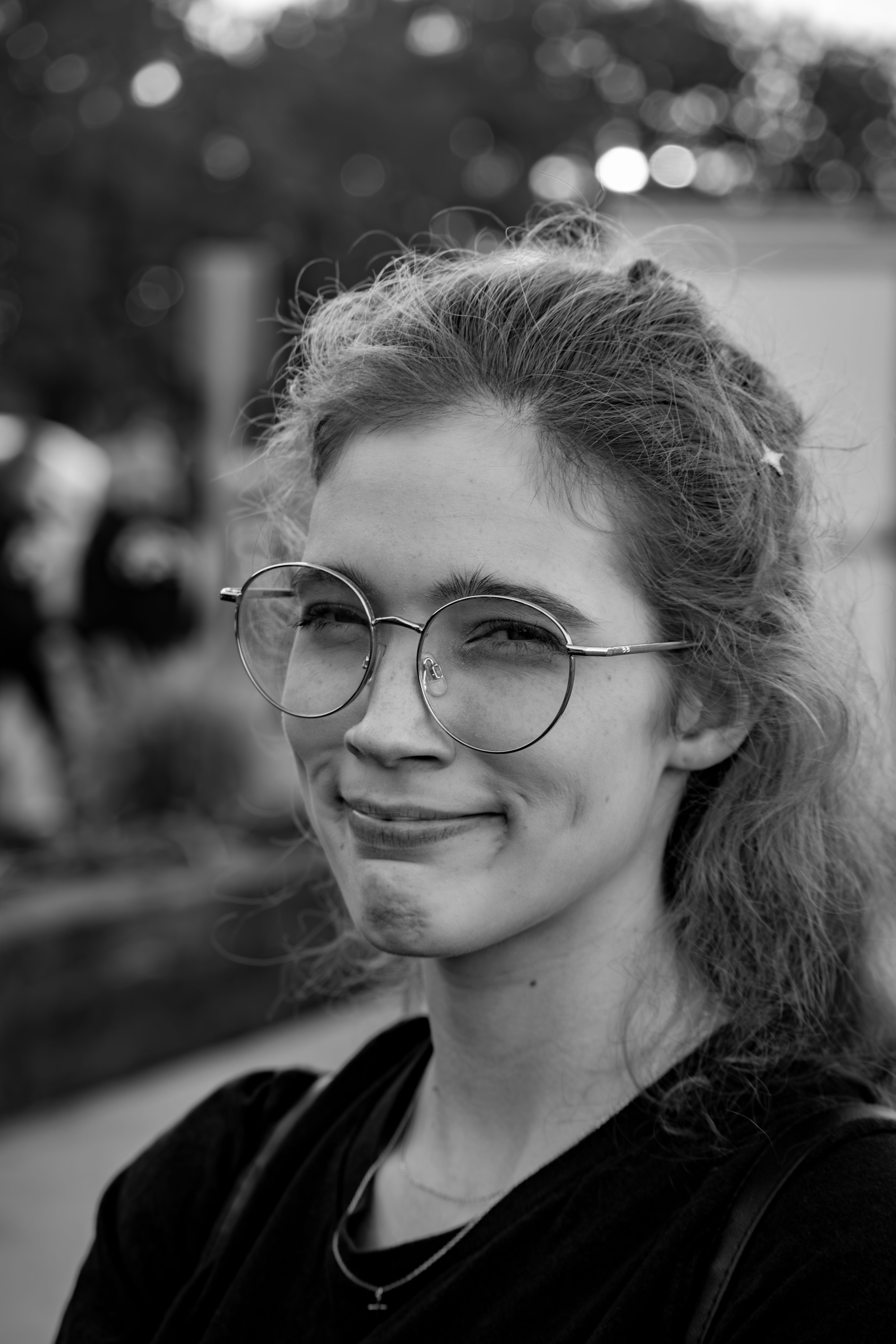 Black and white portrait of a smiling young woman with glasses outdoors