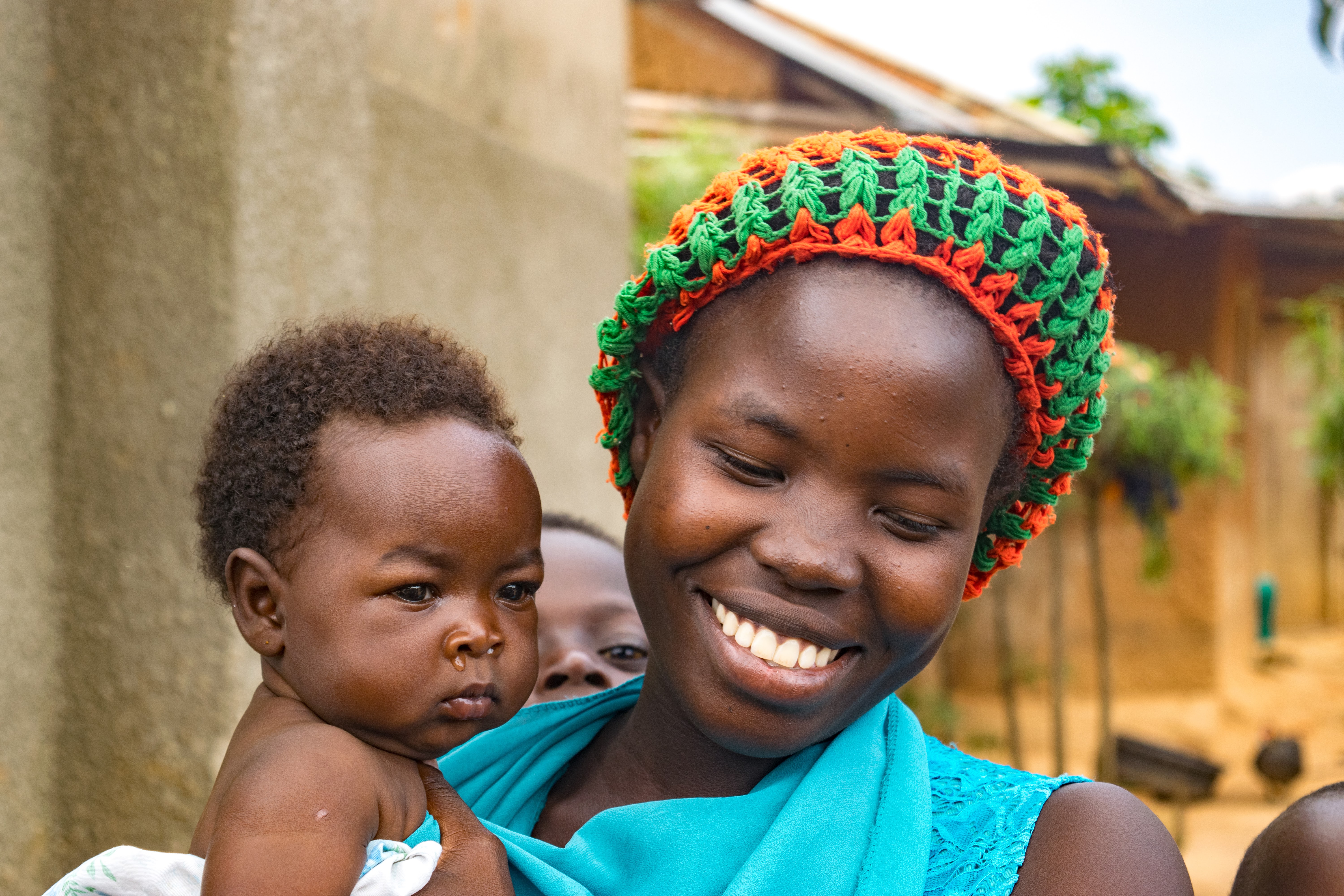 Smiling mother holds her baby outdoors with a warm, joyful expression