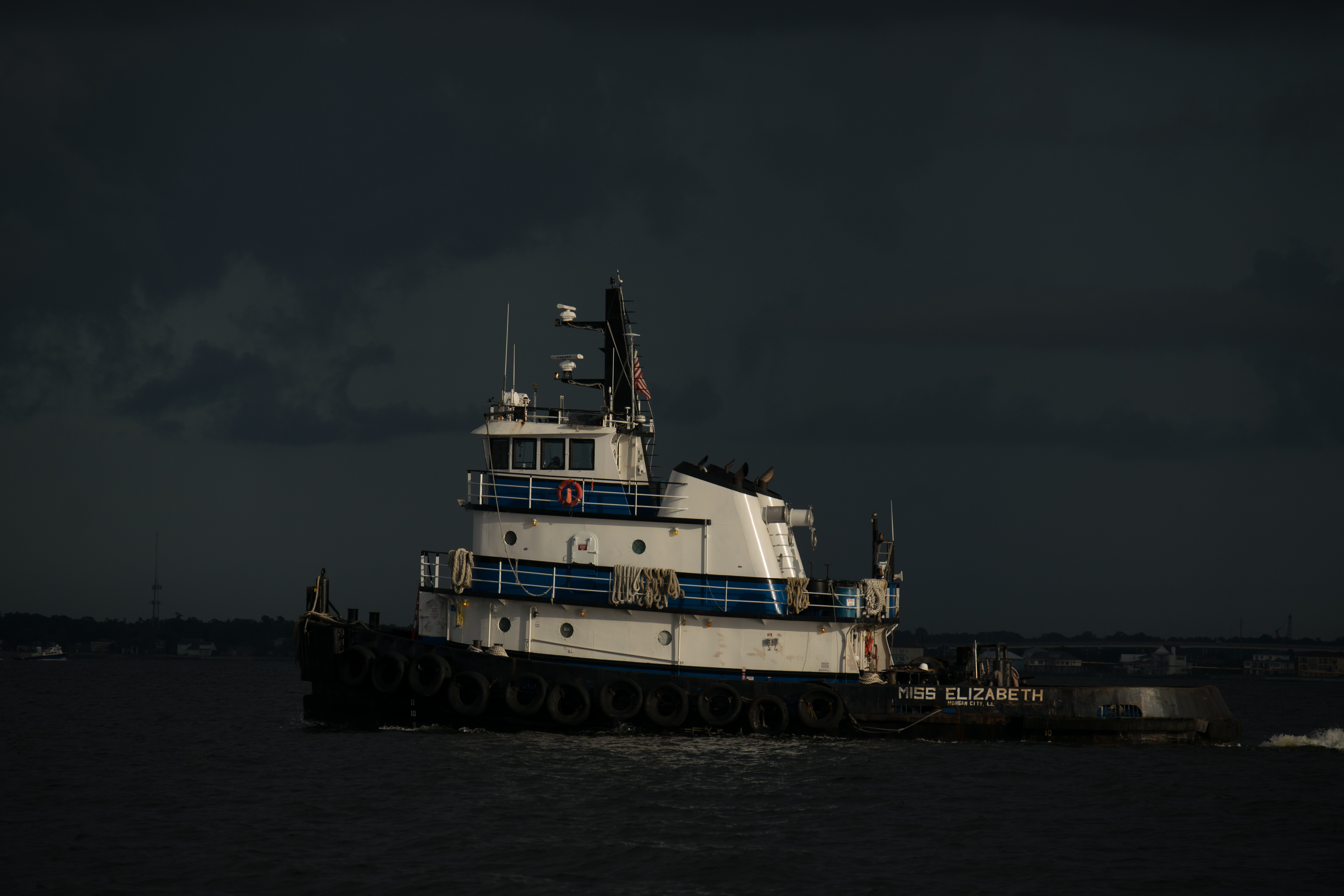 Tugboat Miss Elizabeth navigates dark waters under a stormy sky