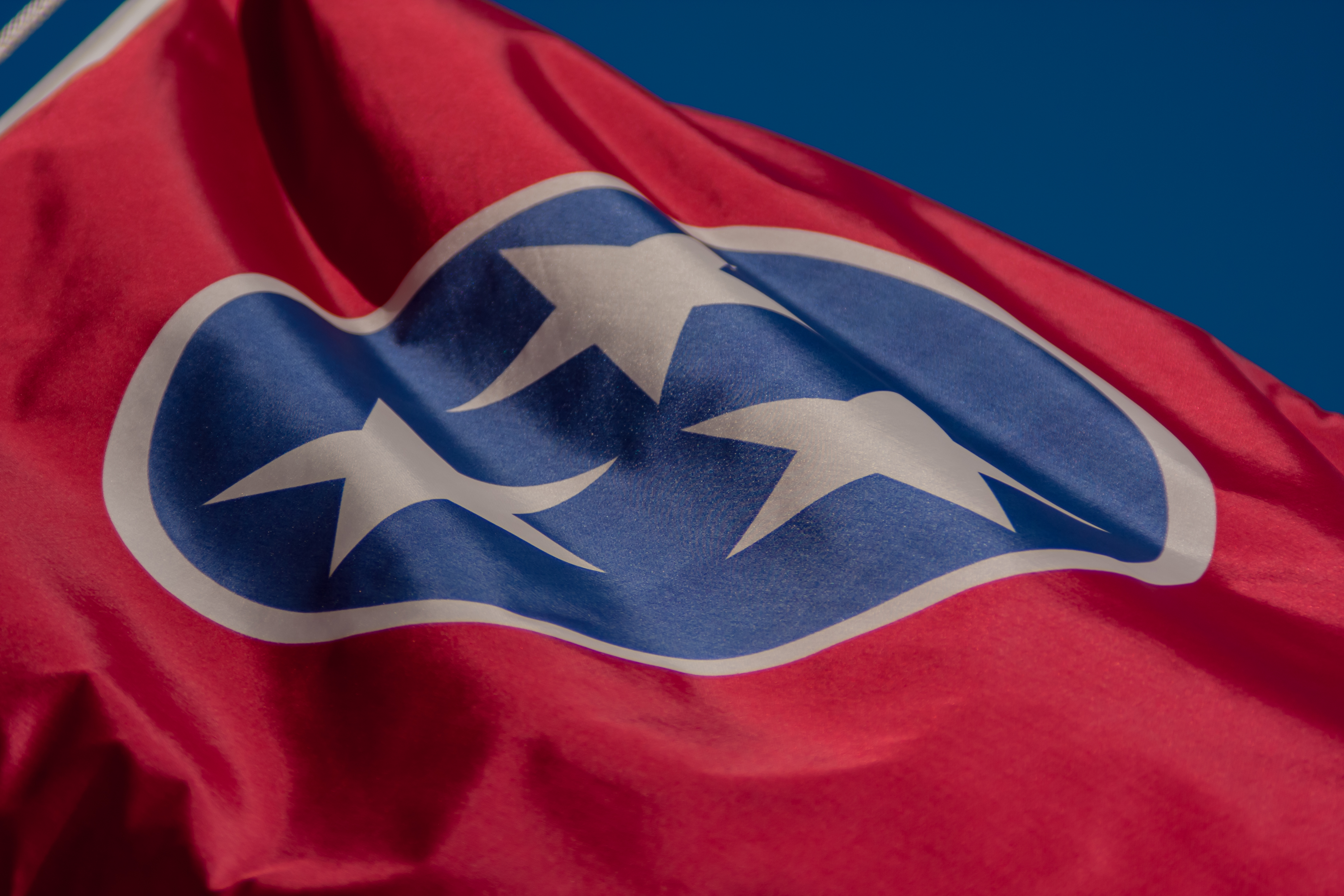 Close-up of the Tennessee state flag waving against a clear blue sky