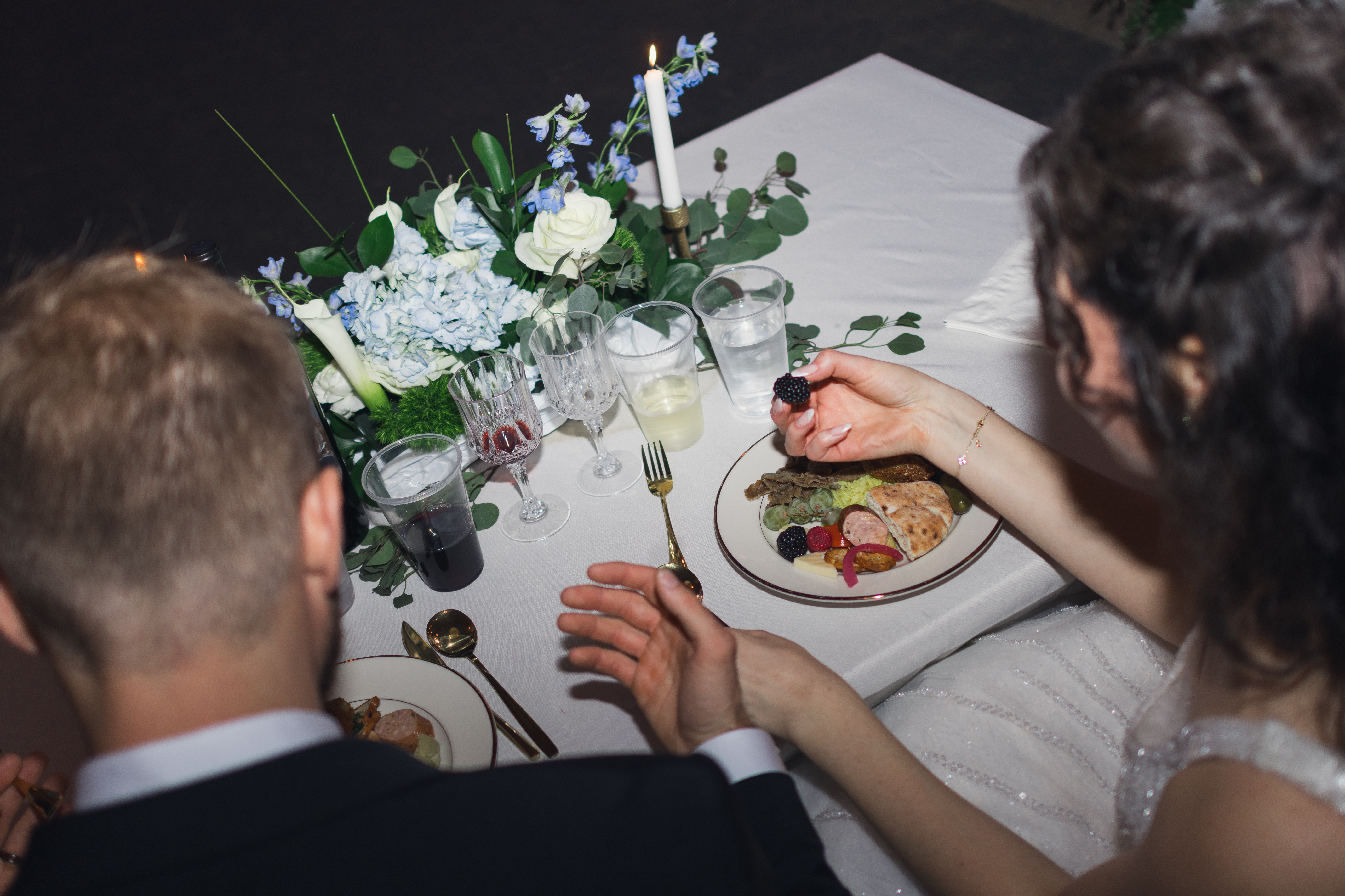 A couple enjoys a romantic wedding reception dinner with floral centerpieces and candlelight