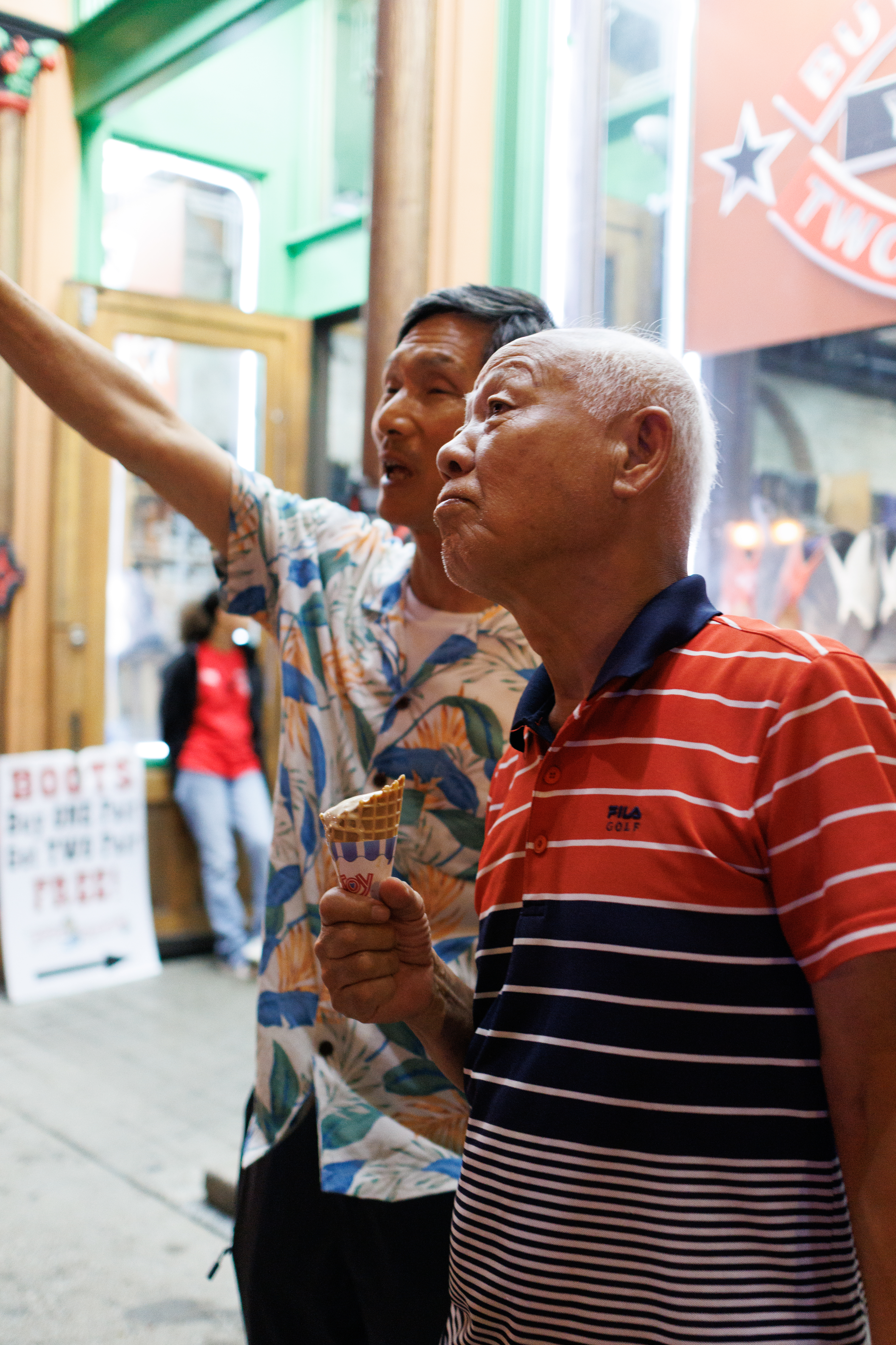 Two men enjoy ice cream on a city street with a blurred background