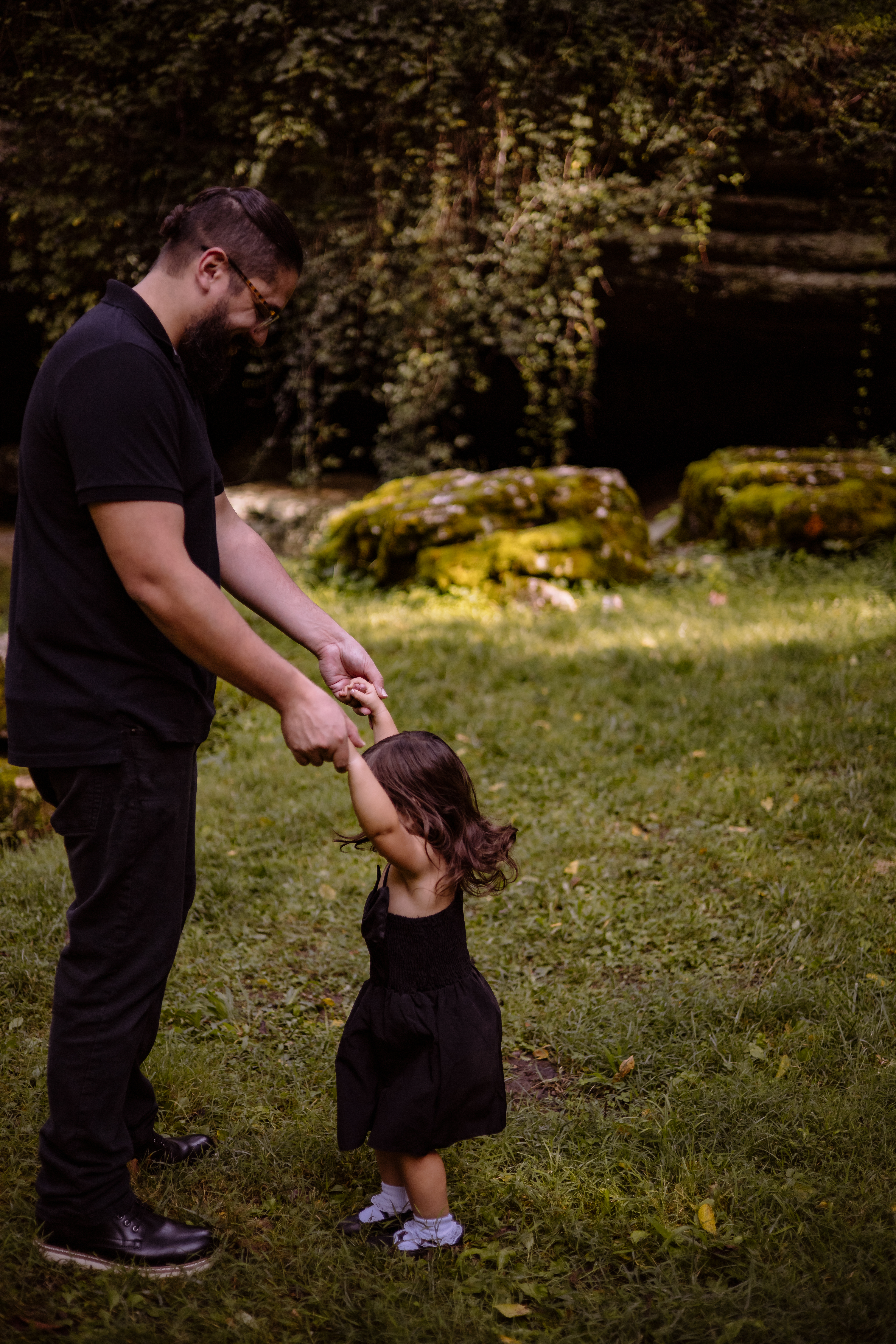 Father and daughter dance happily in a sun-dappled forest clearing